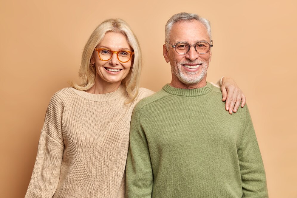 sonriente-pareja-madura-abrazar-mira-alegria-pose-camara-retrato-familia-ninos-felices-vinieron-visitarlos-usan-lentes-transparentes-puentes-casuales-aislados-sobre-pared-marron_273609-47538